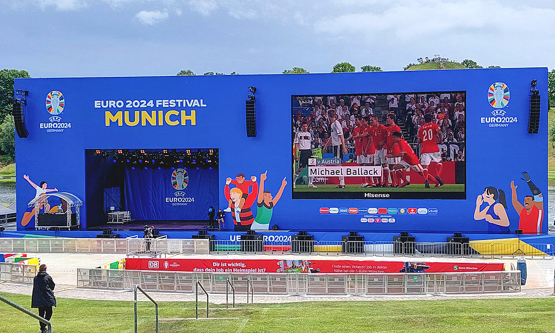 Ein leerer Platz mit einer großen LED-Leinwand, auf der ein Fußballspiel gezeigt wird.