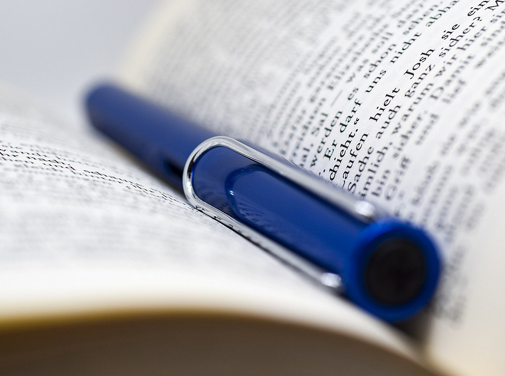 A blue fountain pen lies in an open book. ©Uni Graz/Schwarz