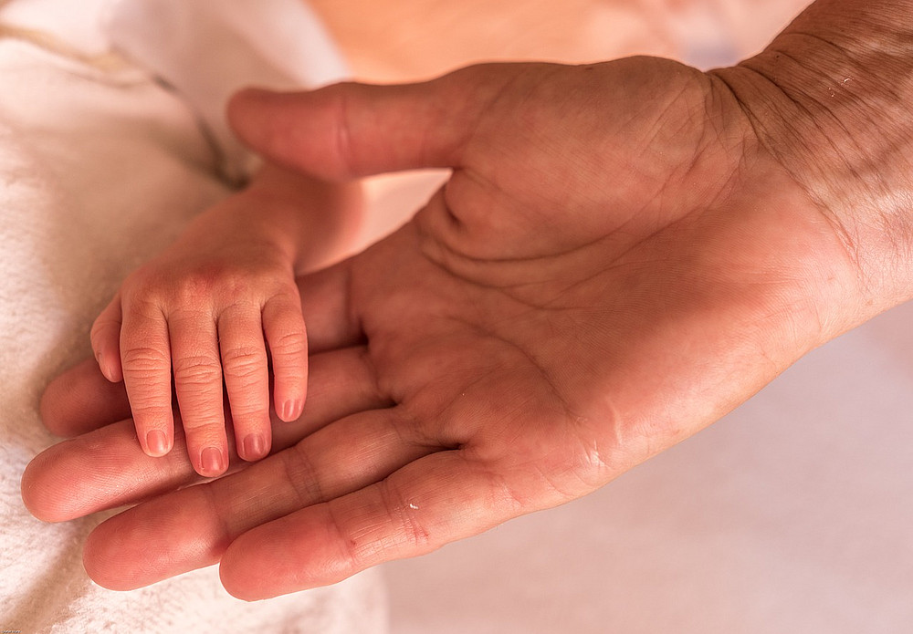Babyhand liegt in großer Hand ©dMz / pixabay