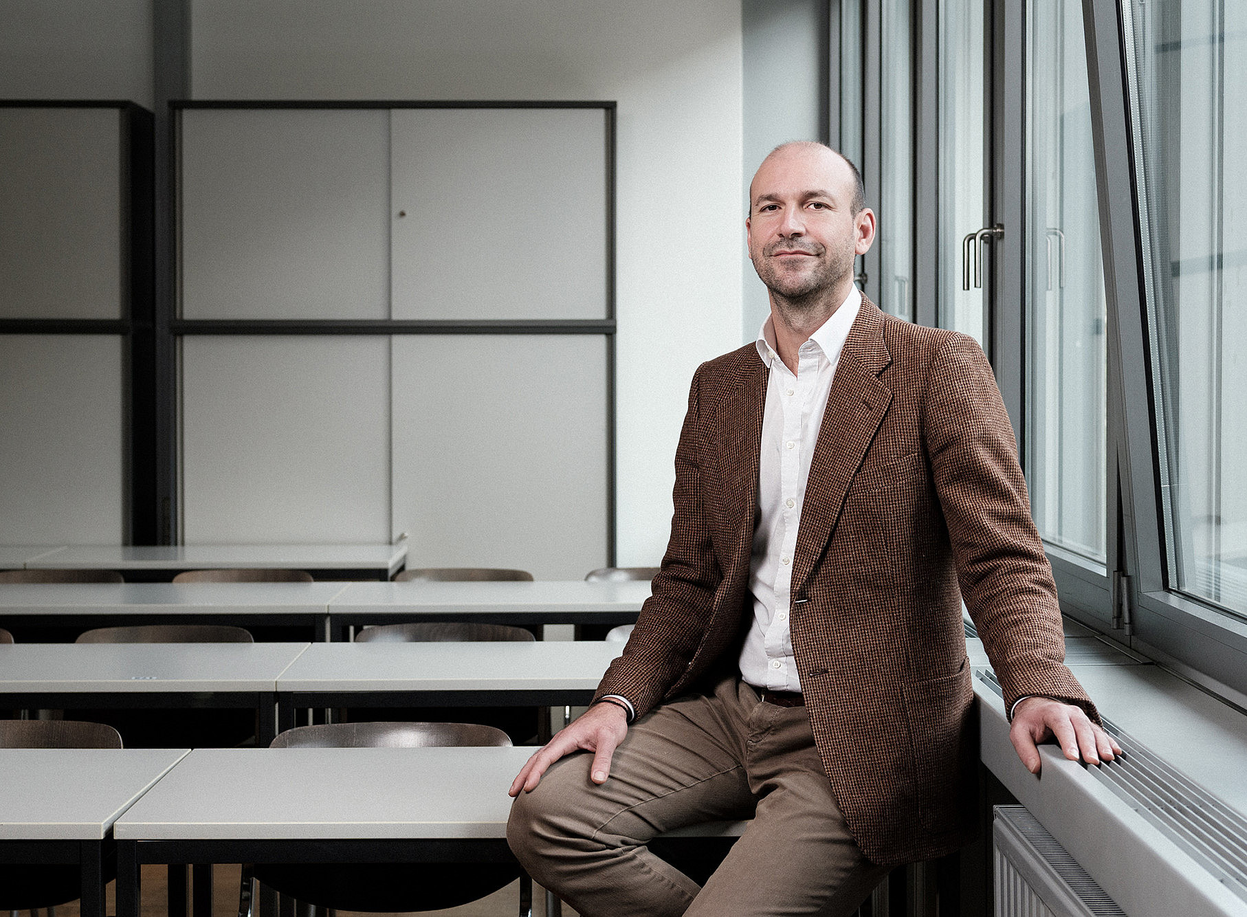 Friedensforscher Maximilian Lakitsch sitzend in einem leeren Hörsaal 