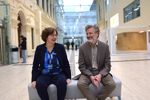 Edeltraud Aspöck und Julian Blunk sitzen auf einer Bank im Foyer der UB Graz und blicken sich an. ©Ulrike Freitag, Uni Graz