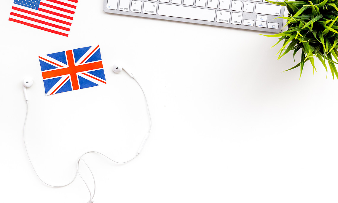 Computer keyboard, headphones, british and american flags on white background top view copy space