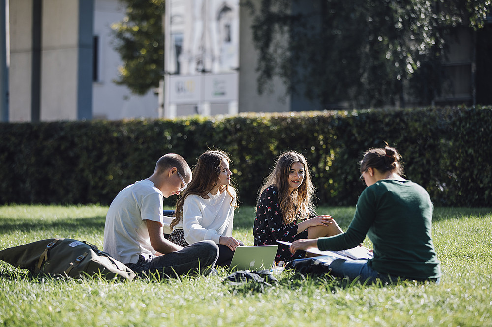 4 Studierende sitzen in einer Wiese ©Uni Graz/Kanizaj