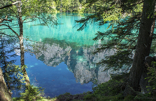 Fotografie des grünen Sees in Tragöß. Berge spiegeln sich in türkisem Wasser.