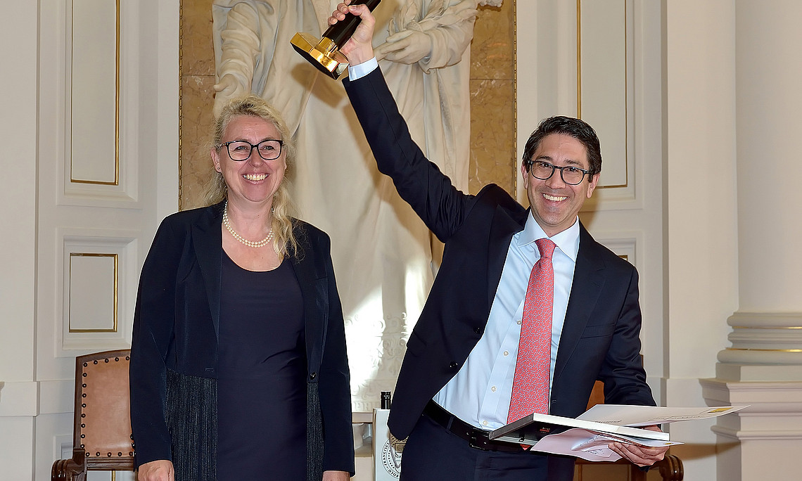 Walter Doralt hält die Seraphine-Puchleitner-Preis-Trophäe in die Höhe, neben Catherine Walter-Laager in der Aula