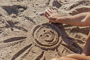 One person has drawn the image of a sun in the sand with their finger. ©Pexels/Kindel Media