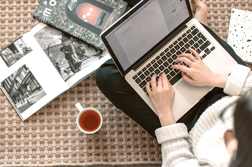 Person sitzt vor aufgeklappten Laptop und einer Tasse Kaffee und arbeitet. ©pexels.com