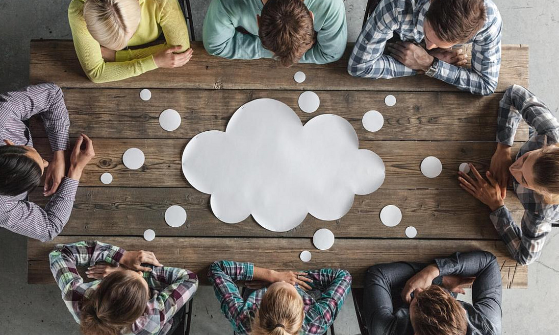 people sitting around a table with a shared thinking bubble on the table