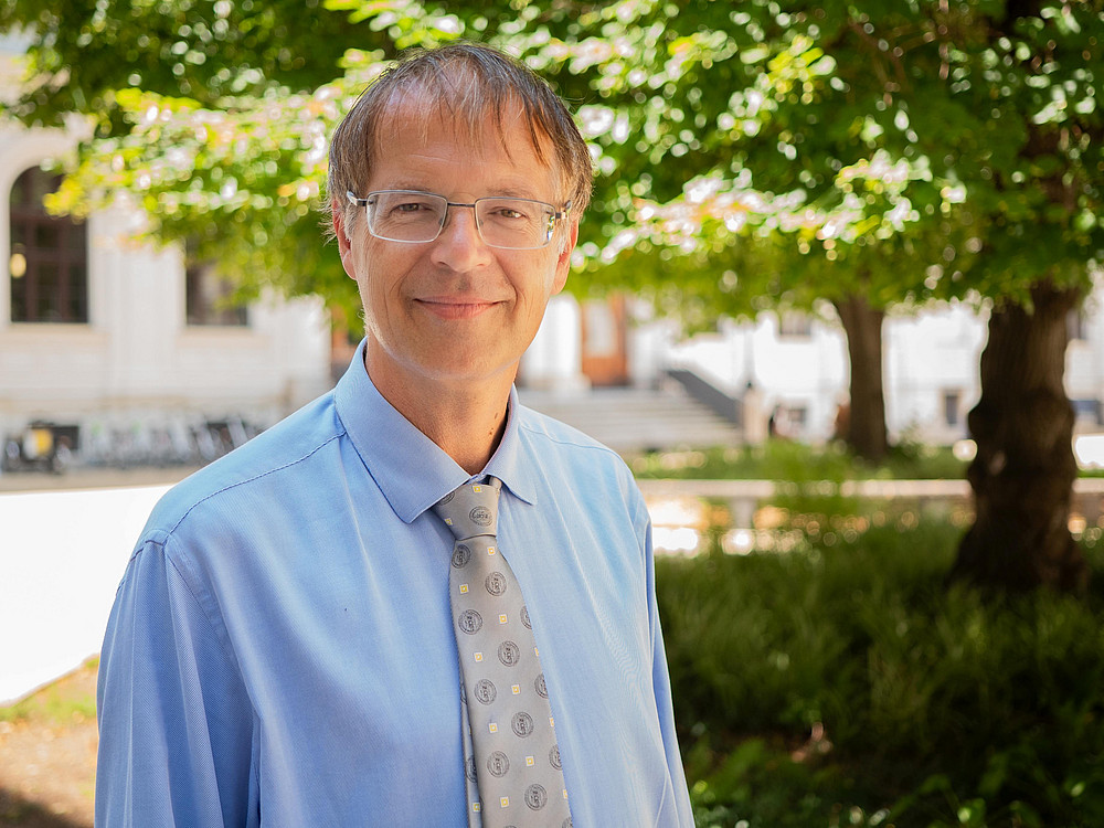 Prof Bernd Wieser, Portraitaufnahme im Innenhof des Hauptgebäudes der Universität Graz. Im Hintergrund ein Baum ©Uni Graz/Radlinger