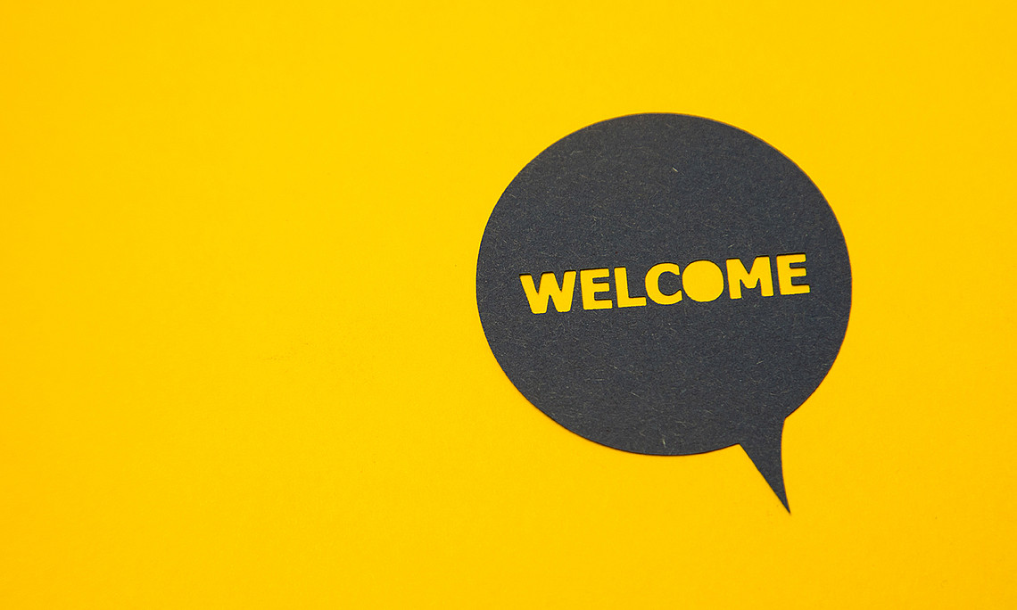 eine schwarze Sprechblase auf gelbem Hintergrund, in der "Welcome" geschrieben steht