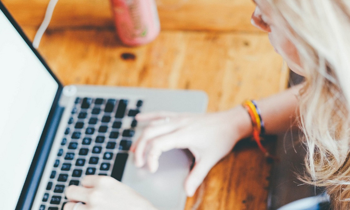 Studierende sitzt konzentriert vor aufgeklapptem Laptop