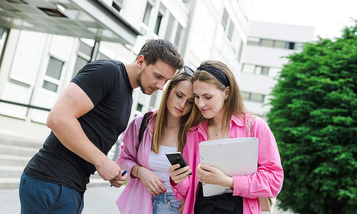 three students with a mobile phone