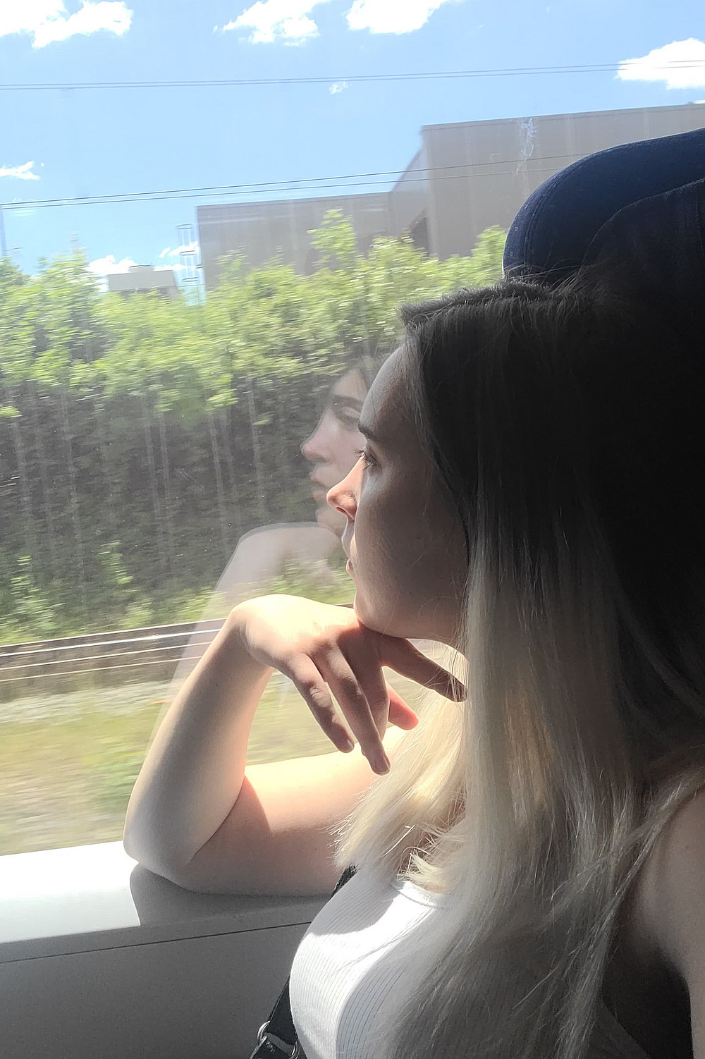 Frau sitzt in einem Zug und schaut nach draußen 