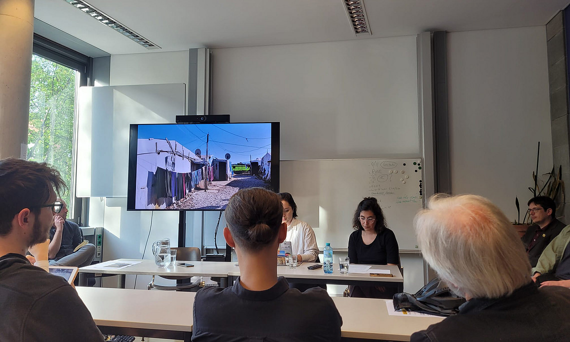 Foto des Panels vom Publikum aus, Bilder laufen im Hintergrund ab