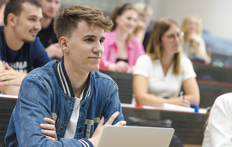 Studierende sitzen lächelnd im Hörsaal