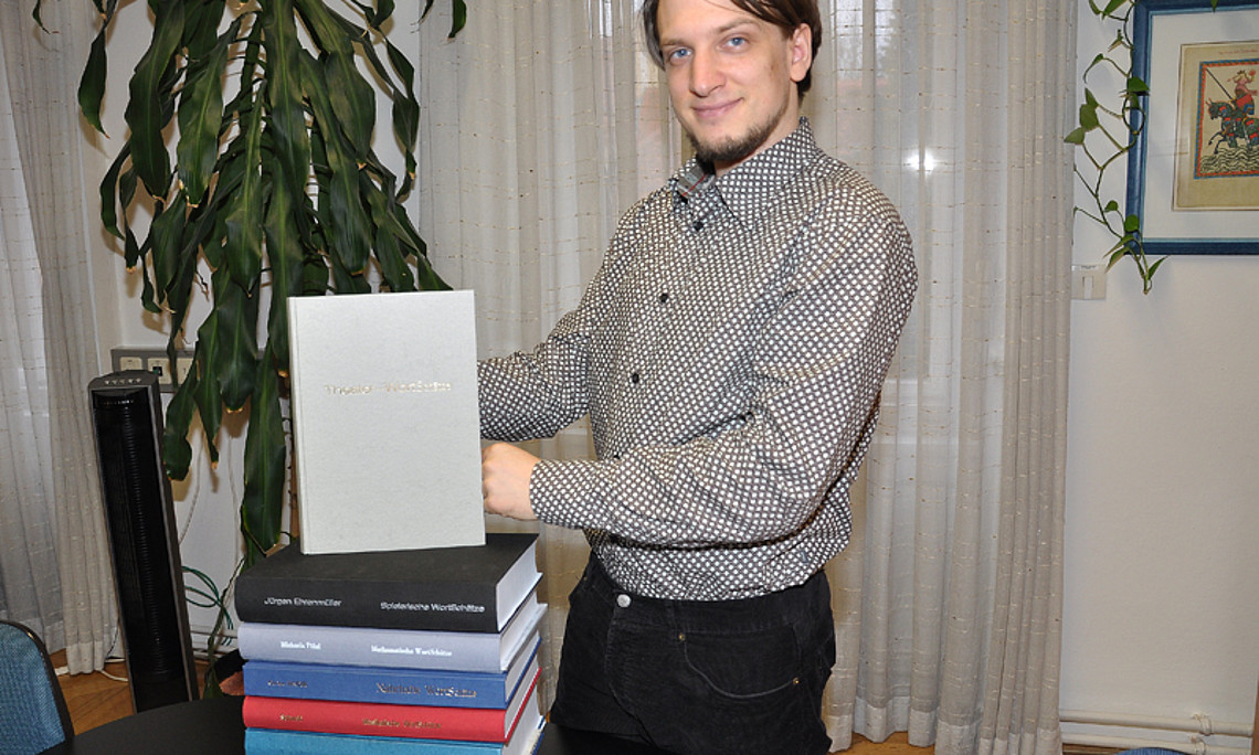 Jakob Reichsöllner mit seiner Masterarbeit. Es ist die achte in der Sammlung der Deutschen WortSchätze.