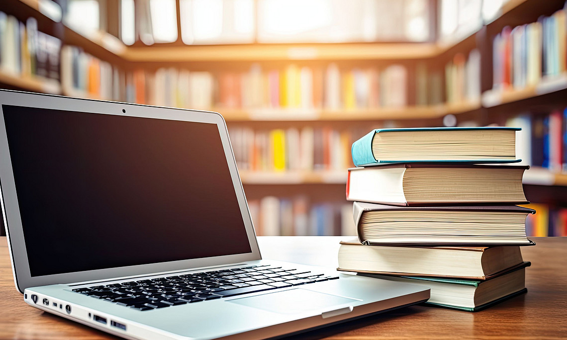 Ein aufgeklappter Laptop und ein Bücherstapel