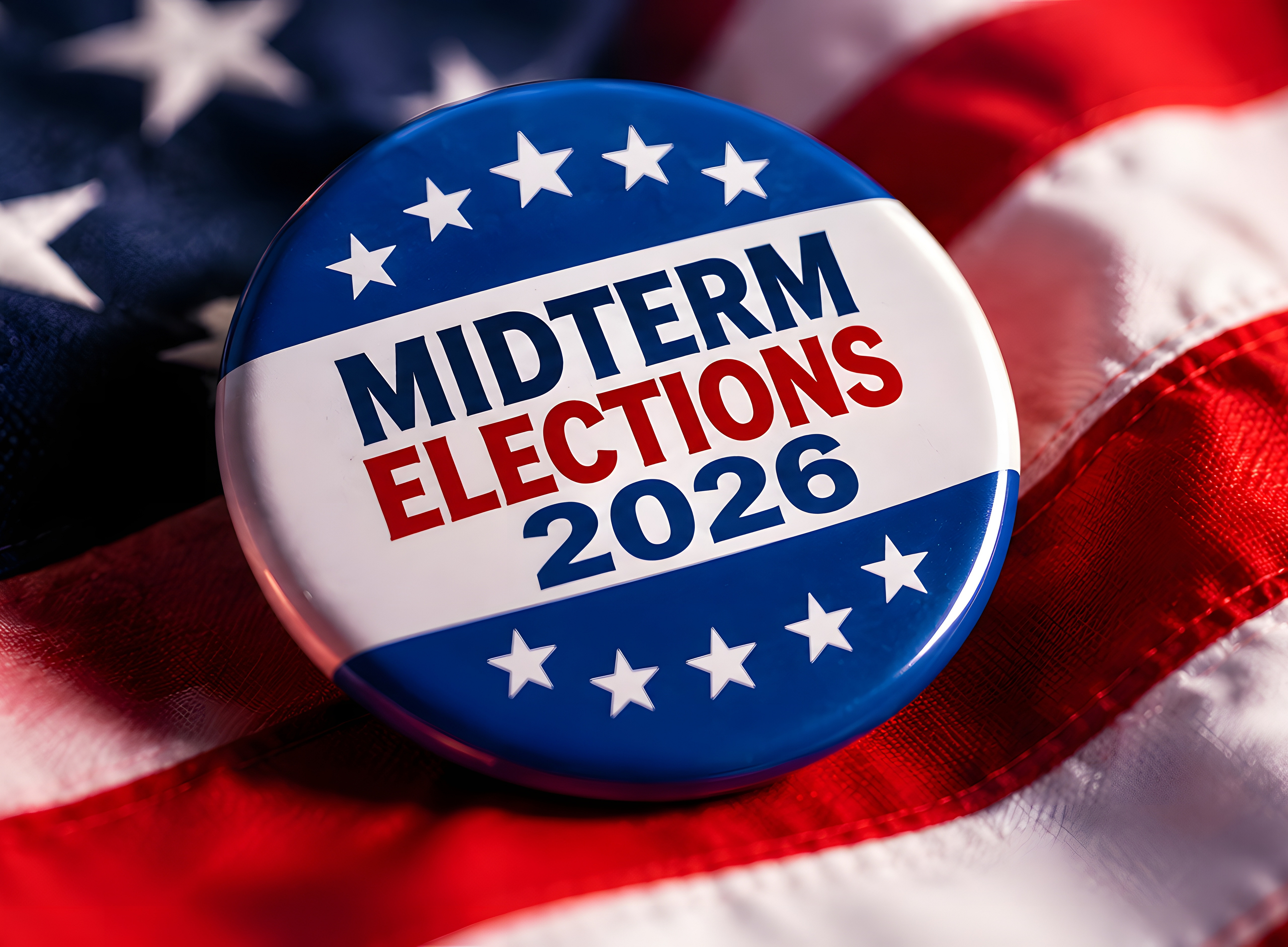 Ein runder Button mit der Aufschrift „Midterm Elections 2026“ liegt auf einer amerikanischen Flagge. Der Button ist in den Farben Blau, Weiß und Rot gestaltet und zeigt mehrere weiße Sterne. 