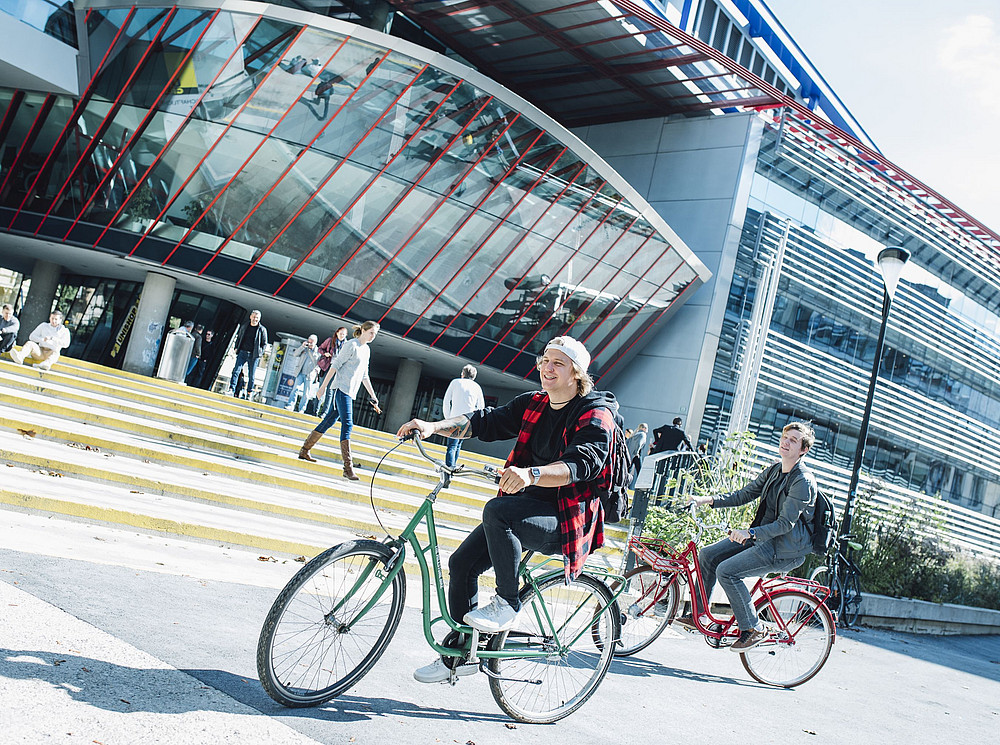 Personen fahren mit dem Fahrrad über den Campus der Uni Graz ©Uni Graz / Kanizaj