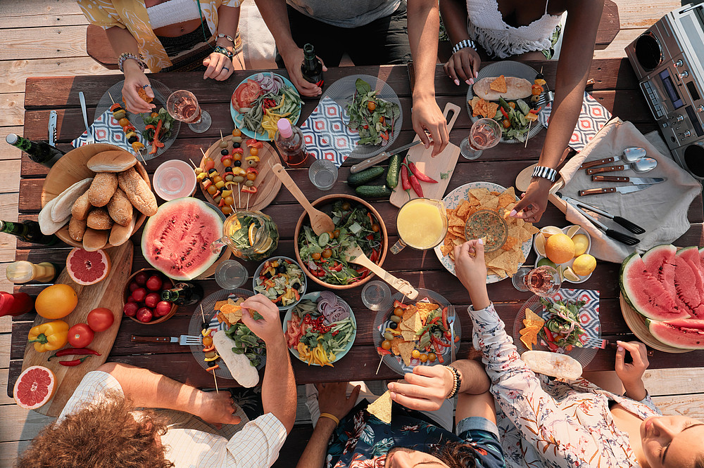 High angle view of group of people sitting at the table and have dinner they celebrating the holiday outdoors ©AnnaStills - stock.adobe.com Ein Tisch mit verschiedenen Speisen ©AnnaStills - stock.adobe.com