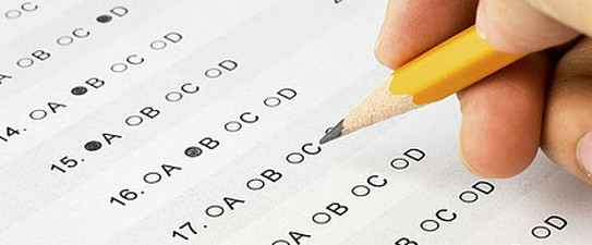 Hand completing a multiple choice exam.