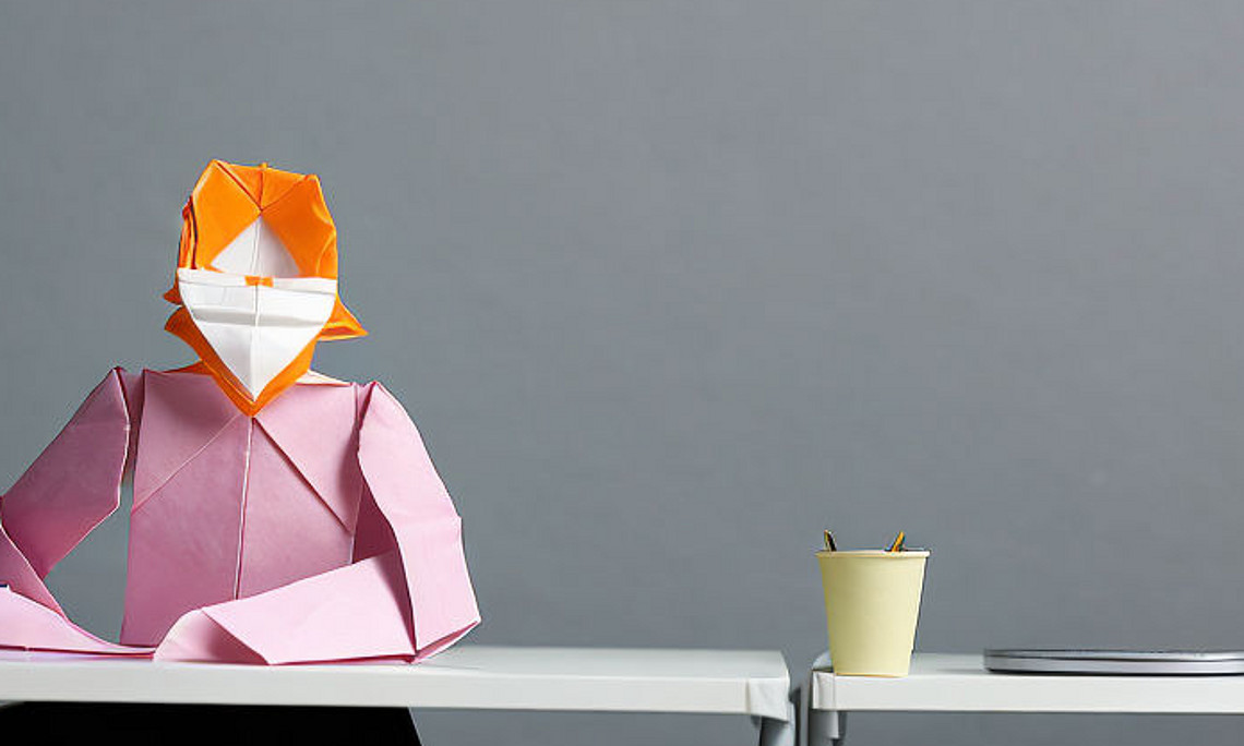 Origami-Person an einem Schreibtisch