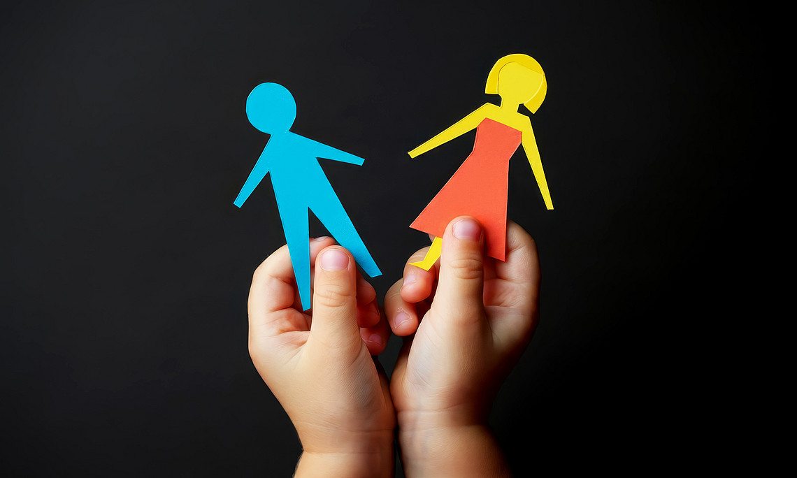 Children's hands holding a female and a male figure