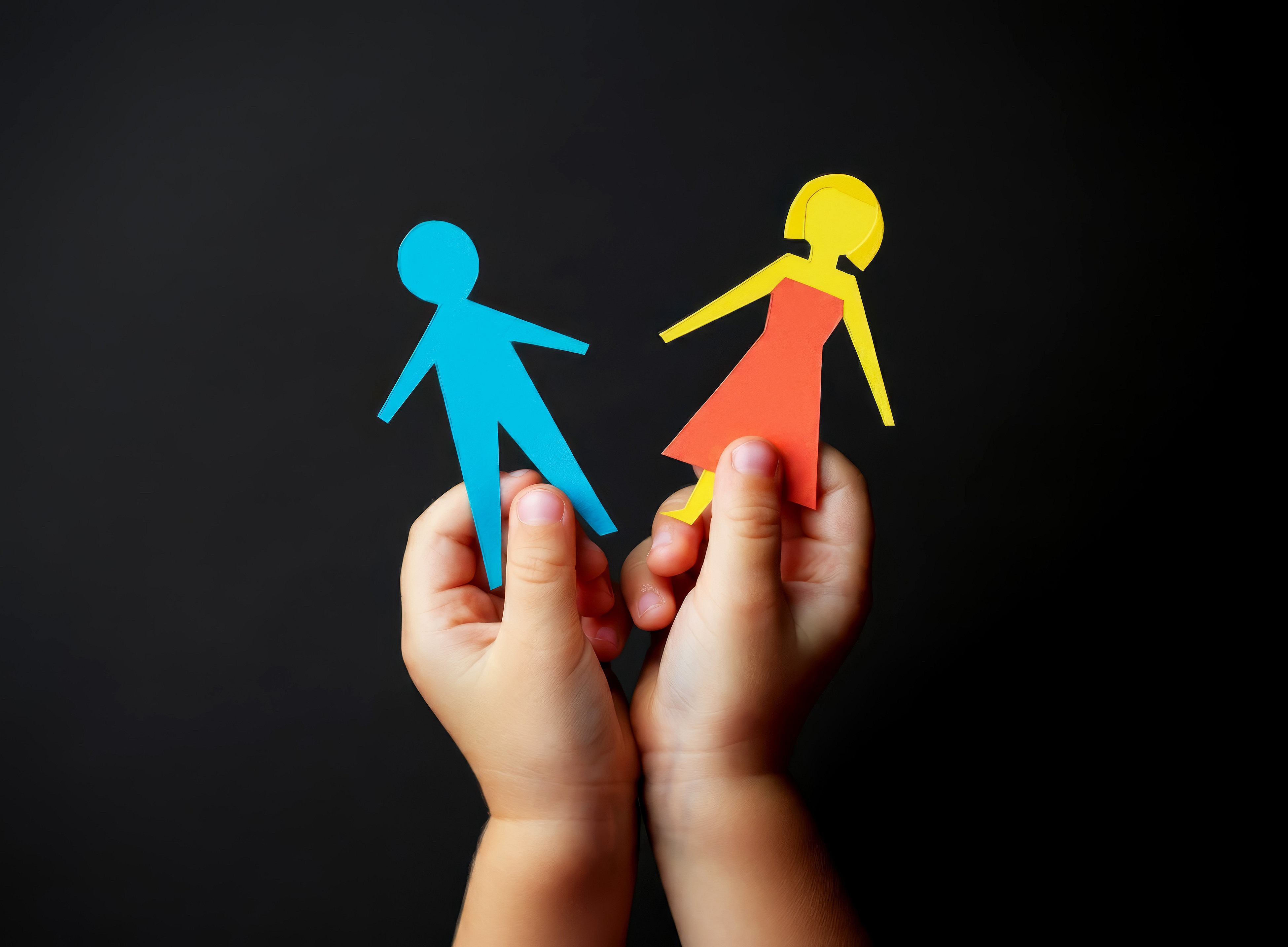 Kinderhände halten eine weibliche und eine männliche figur 