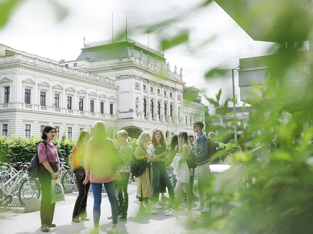 Students on the campus of the University of Graz with the main building in the background ©Uni Graz/Kanizaj