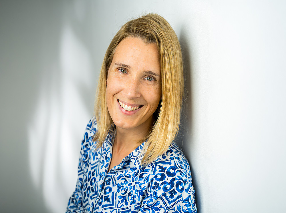Portraitaufnahme M. Jandrisits in blau-gemusterter Bluse vor hellem Hintergrund ©Opernfoto