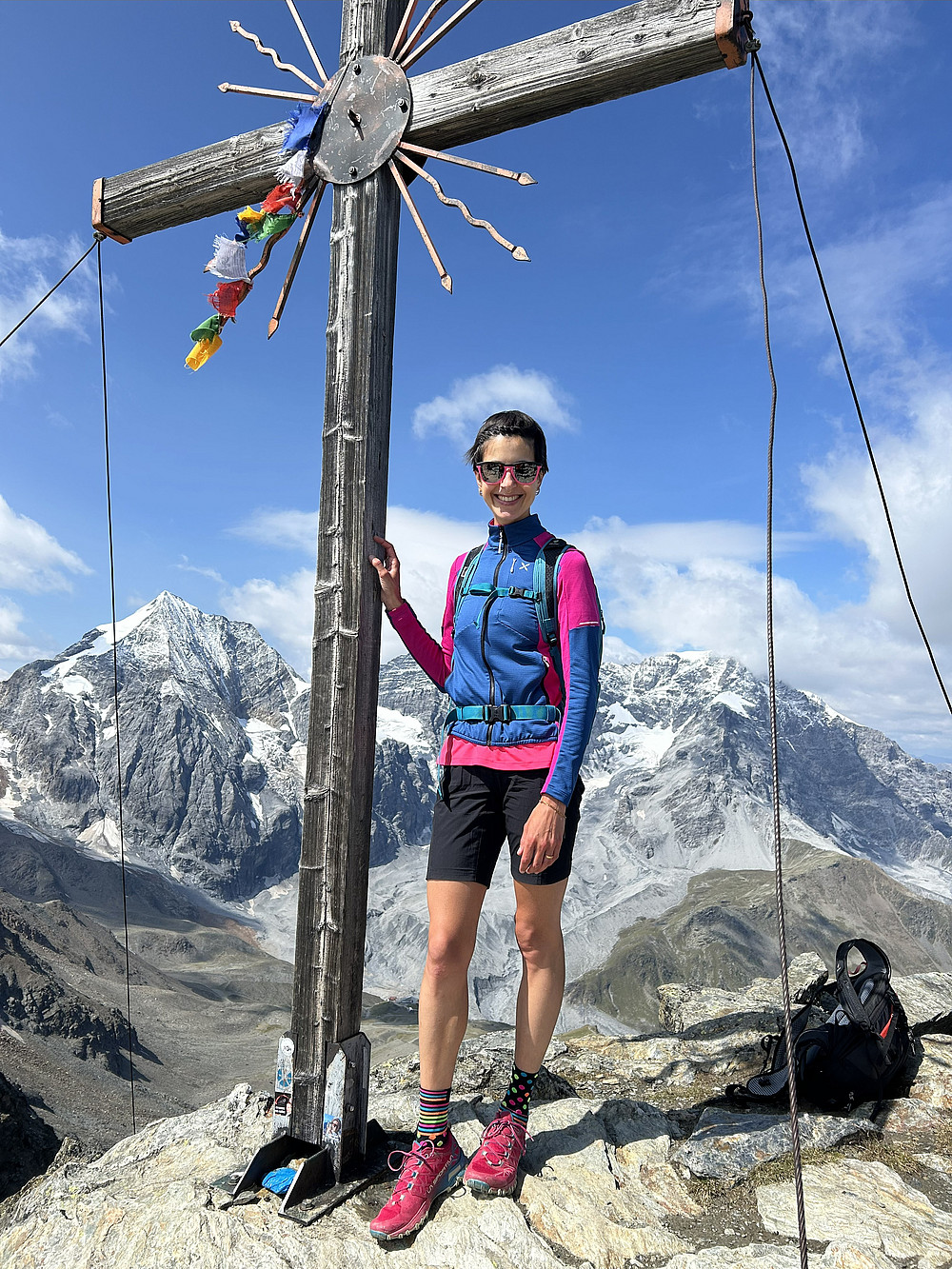 Person auf Berg vor Gipfelkreuz 