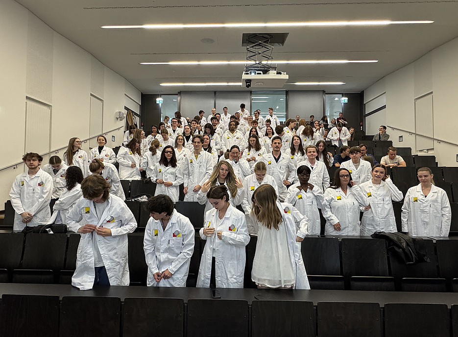 Studierende beim anziehen der neuen Labormäntel 