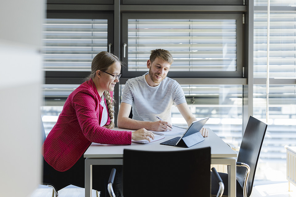 Zwei Studierende unterhalten sich in einem Büro