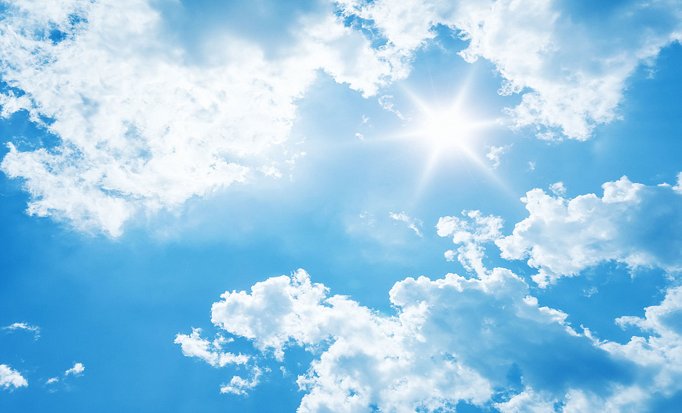 blauer Himmel mit weißen Wolken und Sonne