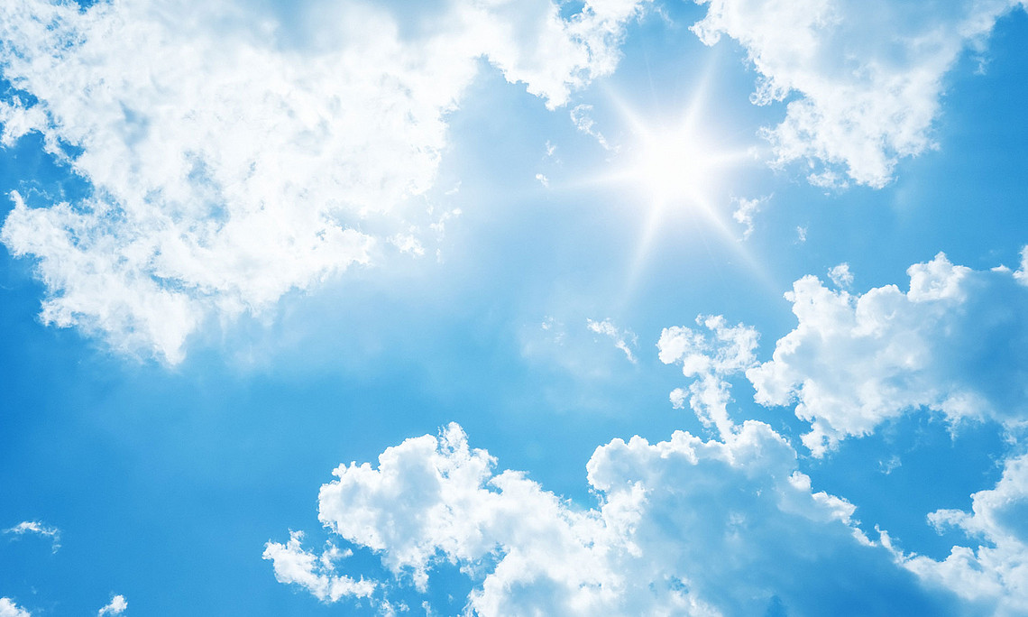 blauer Himmel mit weißen Wolken und Sonne