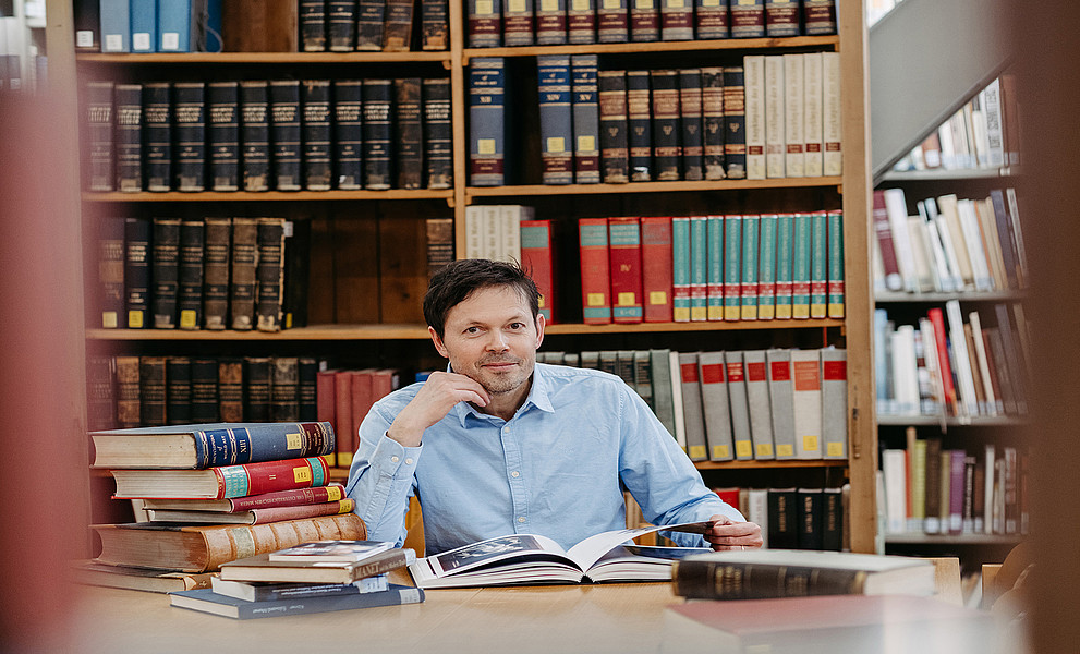 Robert Felfe sitzt in der Bibliothek des Instituts für Kunst- und Musikwissenschaft