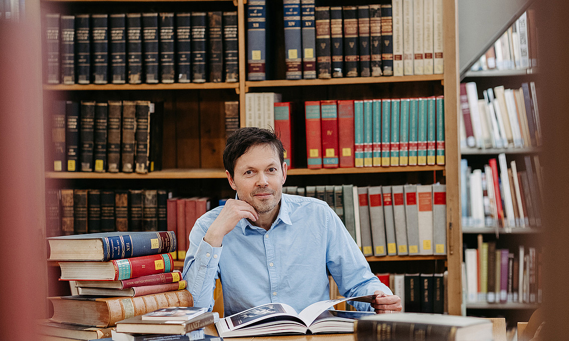 Robert Felfe sitzt in der Bibliothek des Instituts für Kunst- und Musikwissenschaft