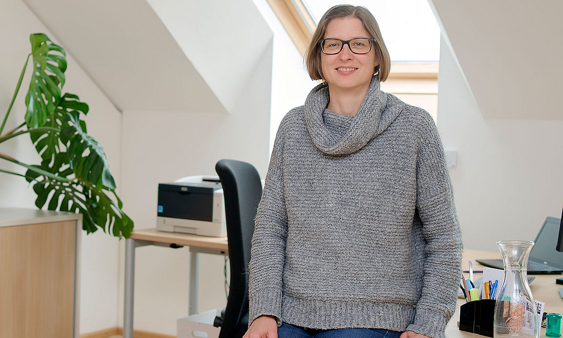 Arbeitspsychologin Bettina Kubicek lehnt am Schreibtisch in ihrem Büro