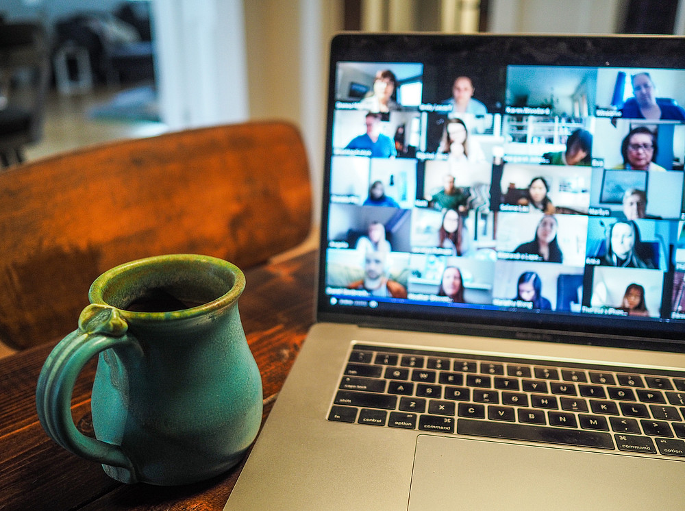 Aufgeklappter Laptop mit Videokonferenz, türkise Tasse im Vordergrund ©Chris Montgomery; unsplash.com