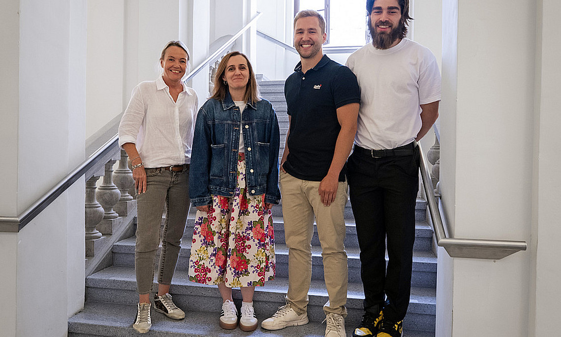 Das Team um Eva Roblegg bestehend aus Atida Selmani, Lukas Vergeiner und James MacFarlane Hoad stehen nebeneinander auf der Stiege