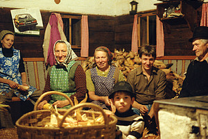 A farming family, six people from three generations, in a parlour with a basket full of unpeeled corn cobs.