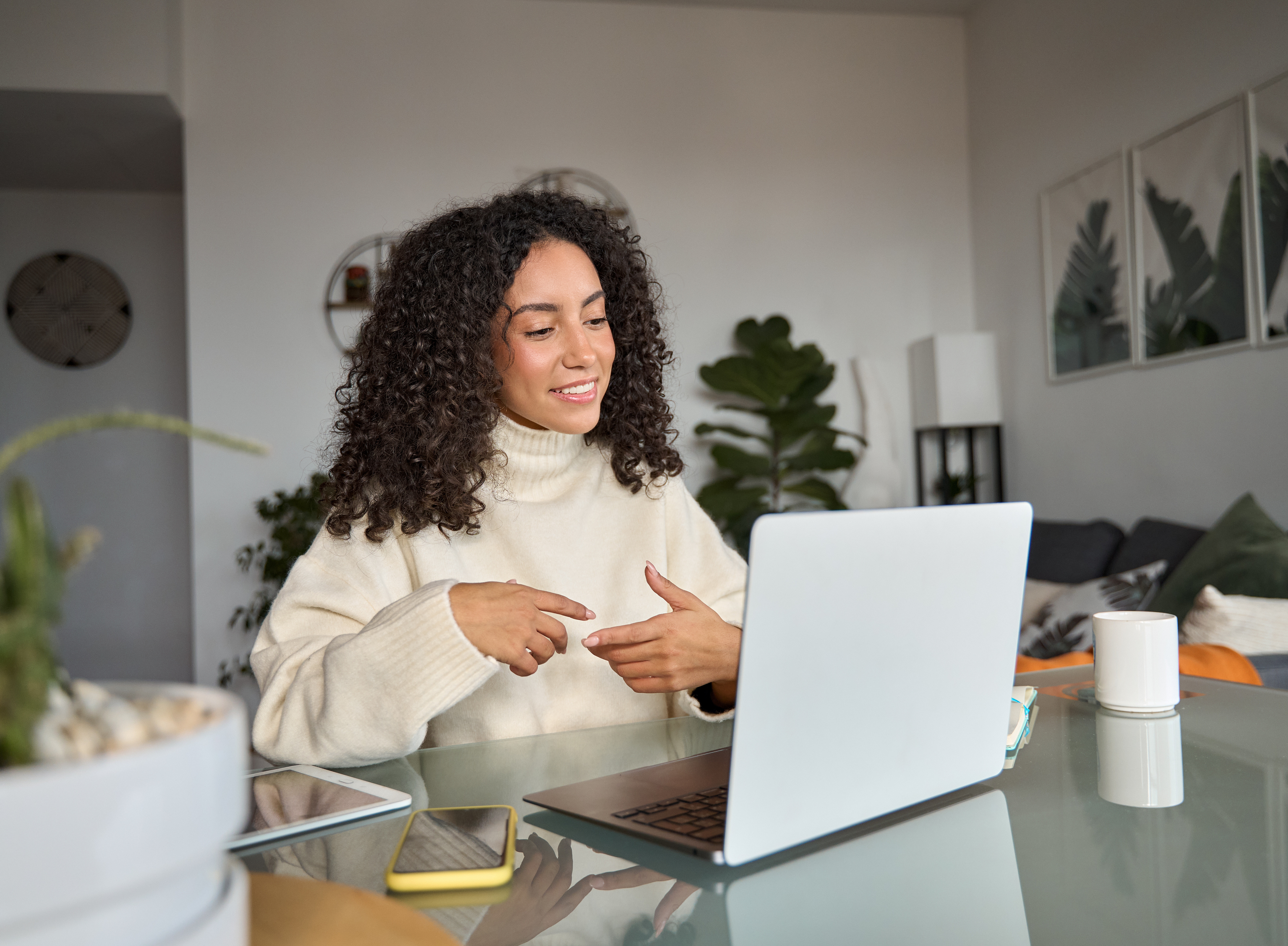 Young woman sitting in front of her laptop in her apartment and taking part in an online meeting. ©insta_photos