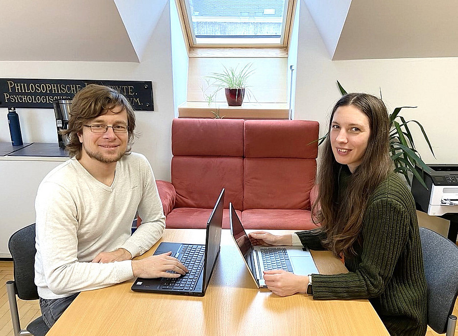 Hilmar Brohmer and Ziva Korda are sitting opposite each other at a desk. 
