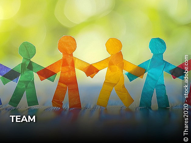 bunte Papiermännchen vor grünem Hintergrund, die sich an den Händen halten 