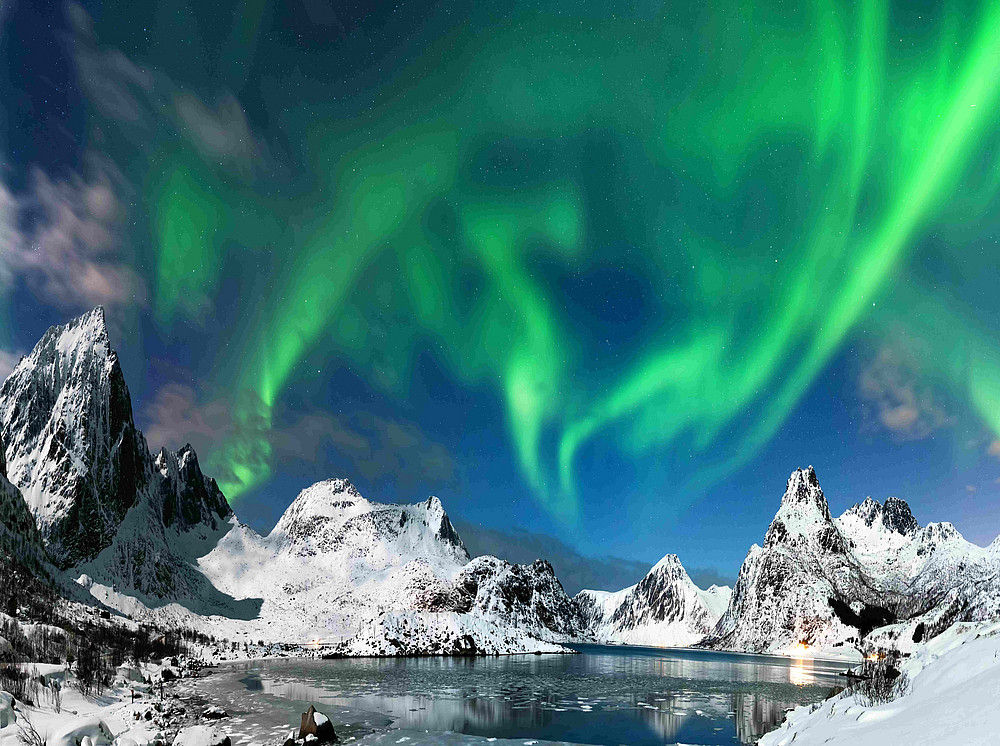Aurora borealis über einer verschneiten Gebirgskette ©Piotr Krzeslak - stock.adobe.com