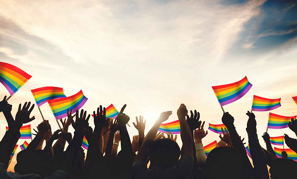 Menschen halten Rainbow-Fahnen in die Höhe
