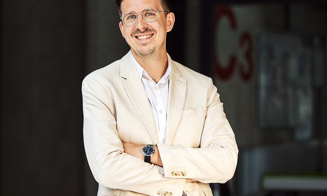 Herr Dr. Joham in hellem Anzug im Stiegenhaus des Rewi-Gebäudes