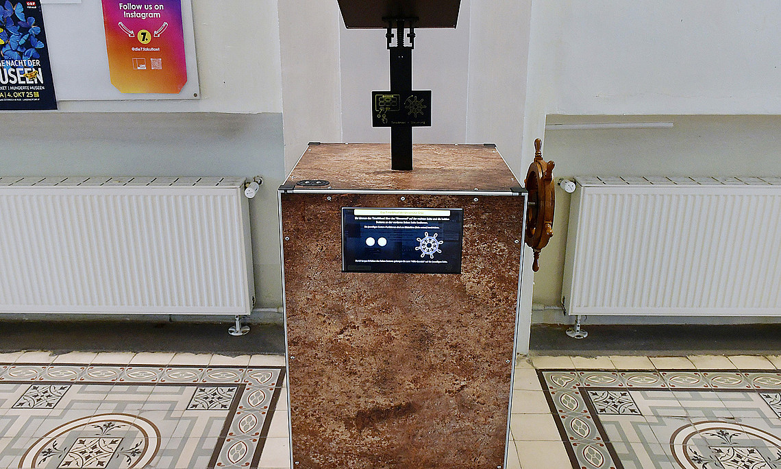 the Time Wheel, a metal box with an eyepiece, a wheel for turning on the side, two buttons and a display on the front