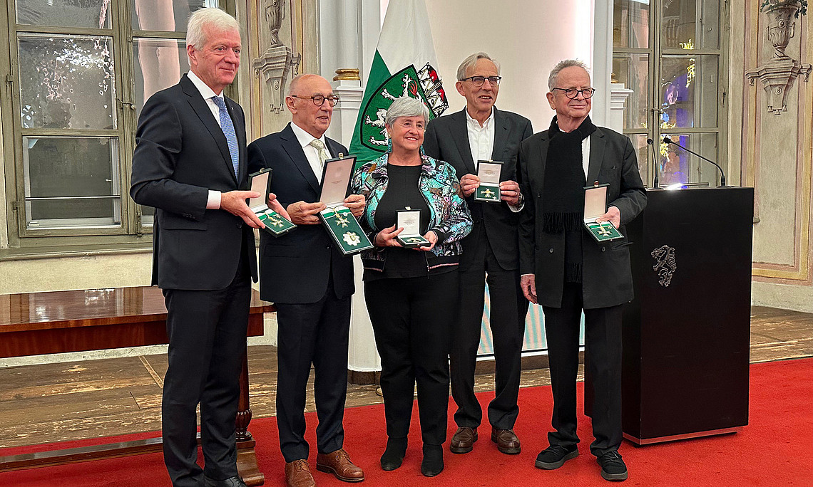 eine Frau und 4 Männer, die nebeneinander stehen und Ehrenzeichen des Landes Steiermark in den Händen halten