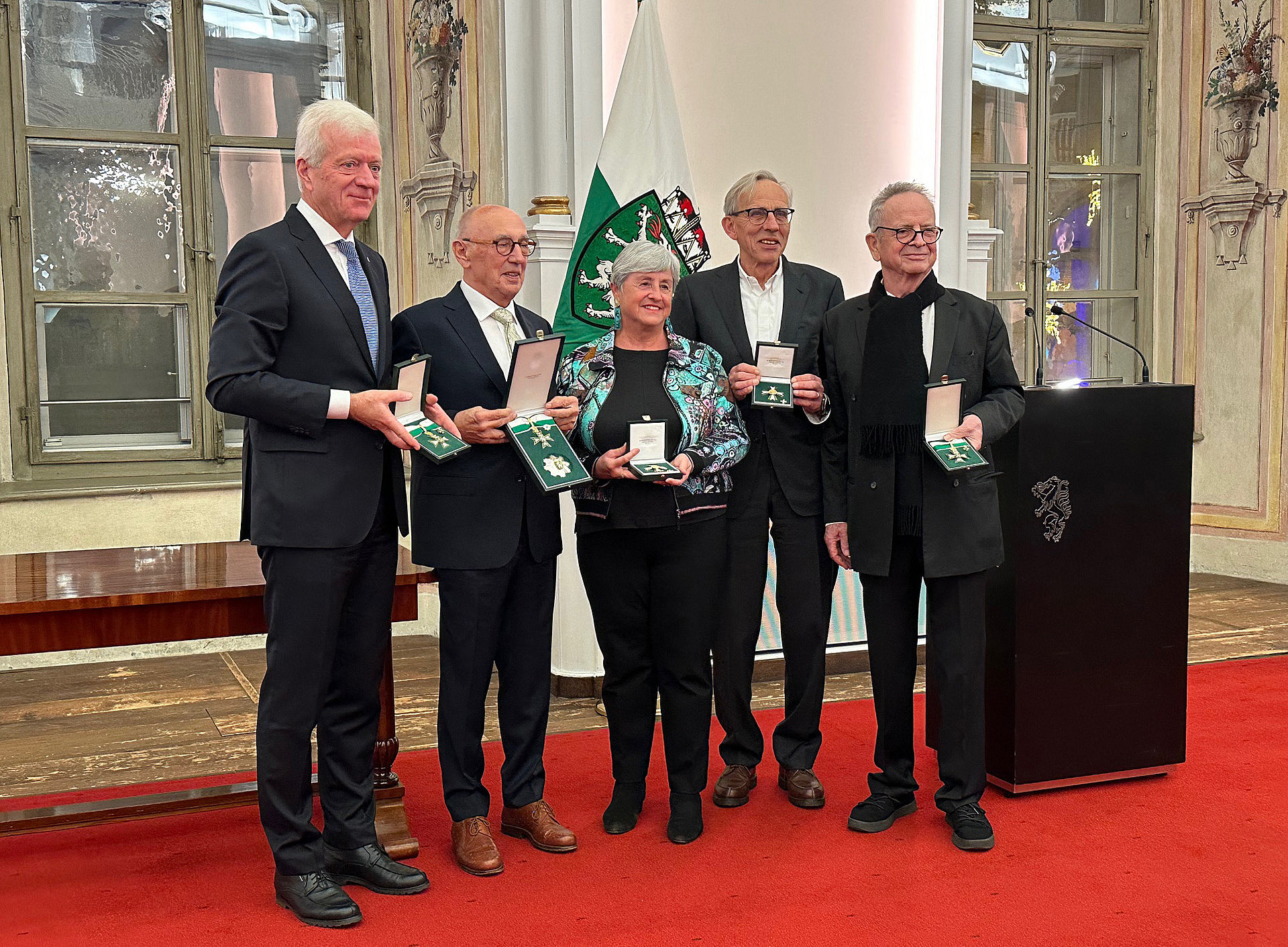 eine Frau und 4 Männer, die nebeneinander stehen und Ehrenzeichen des Landes Steiermark in den Händen halten 